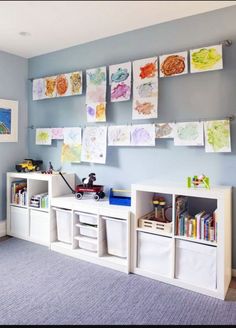 a child's room with blue walls and pictures on the wall, bookshelves and toy bins