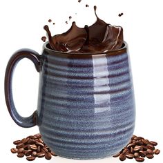 a blue coffee mug with chocolate splashing out of it and coffee beans on the ground