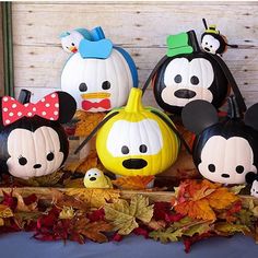 mickey mouse pumpkins and other decorations are on display in front of a wooden wall