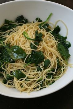 a white bowl filled with pasta and spinach