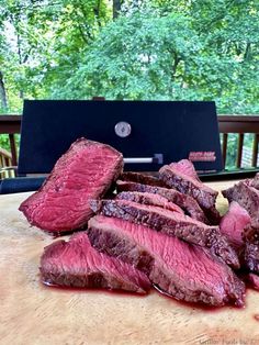 steak sliced up and ready to be cooked on the grill with trees in the background