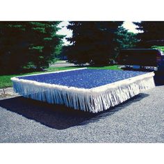 a blue and white table with fringes on it in front of a black truck