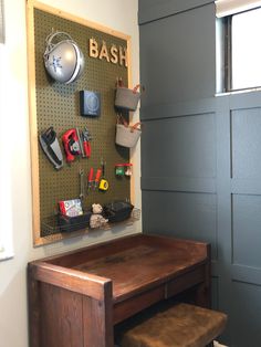 there is a desk and chair in the room with tools hanging on the wall behind it