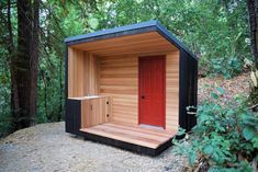 an outdoor sauna in the woods with red door