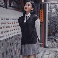 a girl in a school uniform standing next to a wall