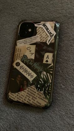 an iphone case with various stickers on it sitting on the floor next to a cell phone