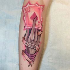 a person with a tattoo on their arm has a hand holding up a playing card