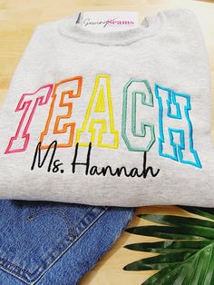 Celebrate the educators in your life with our Personalized TEACH Embroidered Sweatshirt! This cozy sweatshirt features the word TEACH beautifully embroidered across the chest in bold, elegant lettering. To add a unique touch, we personalize it with the teacher's name in delicate cursive below the TEACH embroidery, making it a truly one-of-a-kind piece. Crafted from high-quality, soft, and durable fabric, this sweatshirt is designed to keep teachers comfortable and stylish throughout the day. Ava Embroidery Christmas Gifts, Machine Embroidery Gifts, Name In Cursive, Elegant Lettering, Machine Embroidery Christmas, Custom Embroidered Sweatshirt, School Sweater, Embroidery Stitches Beginner, Custom Teacher Gifts