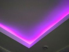 a room with a purple light on the ceiling and a white wall in the background