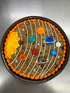 a cake decorated to look like the solar system on a metal surface with orange icing