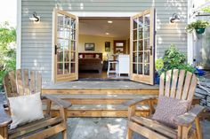 two wooden chairs sitting on top of a patio next to an open door that leads into a living room