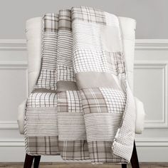 a chair with a blanket on top of it in front of a white wall and wooden floor