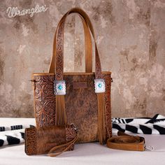 Noted: Due to the natural characteristics of cowhide, each tote bag's cow print may vary slightly. The uniqueness of your bag adds to its charm! Carry Tote Genuine hair-on cowhide Vintage floral tooled strap and Leather tassel on the front Accented with rectangle turquoise stone concho Wrangler logo applique on the front Top zipper closure Inside of the bag includes a zippered pocket and 2 open pockets A zippered pocket on the back to conceal the handgun An open 'W" logo pocket on the back Double flat tooled strap Adjustable crossbody strap included Medium：9.5" (L) X 4"(W) X 9.2"(D) Large: 12.25" (L) X 5"(W) X 11.5"(D) Carry Wallet Made of synthetic Leather Hair-on cowhide on the front Floral tooled pattern Top zipper closure Button closure on the front Multiple card slots and 2 long slot Concealed Carry Purse, Western Chic, Brown Tote, Crossbody Wallet, Small Tote, Leather Tassel, Ear Warmers, Turquoise Stone, Cowhide Leather