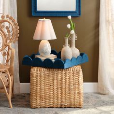 a wicker table with two vases and a lamp on it next to a chair