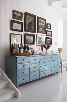 a blue dresser with pictures on the wall above it