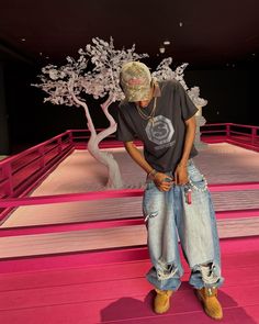 a man standing in front of a fake tree with his hands on his hips