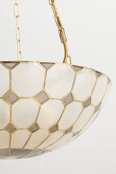 a chandelier hanging from the ceiling with white and gold geometric glass coverings