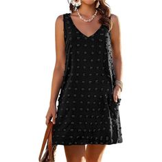 a woman wearing a black dress with polka dots on the side and a handbag