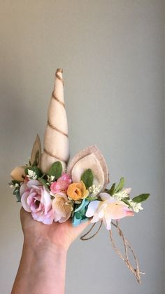 a hand holding a flower arrangement with an unicorn's horn