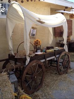 an old wagon is decorated with sunflowers and white drapes for the canopy