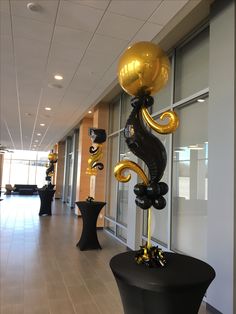 some black and gold balloons are on display in front of a window at an office building