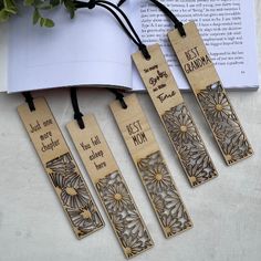 four wooden bookmarks with the words best mom on them sitting next to an open book