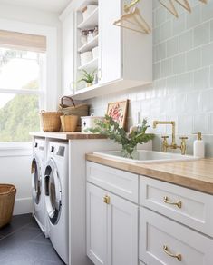 a washer and dryer in a white kitchen with wood counter tops on the side