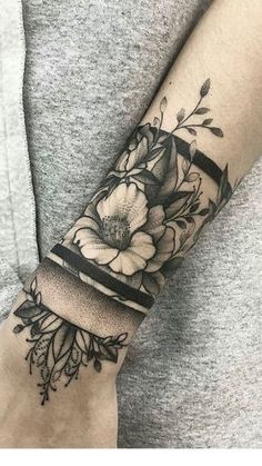 a woman's arm with flowers on it and a black band around the wrist