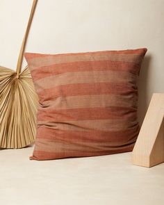 an orange and brown striped pillow sitting on top of a table next to a fan