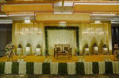 a stage set up for a wedding ceremony with flowers and greenery on the floor