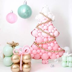 a christmas tree made out of balloons and other decorations on a white background with pastel colors