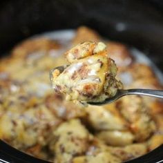 a spoon full of food in a crock pot with meat and cheese on it