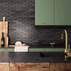 a kitchen with green cabinets and black counter tops, gold faucets and wooden cutting boards