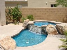 a backyard with a pool and waterfall in the middle