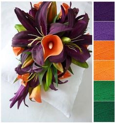 a bouquet of purple and orange flowers sitting on top of a white cloth covered pillow