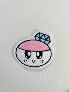 an embroidered patch with a pink hat on it