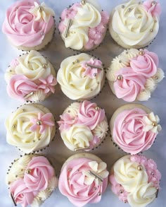 twelve cupcakes with pink and white frosting roses on them are arranged in rows