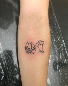 a small black and white tattoo on the arm of a person with a penguin in a helmet