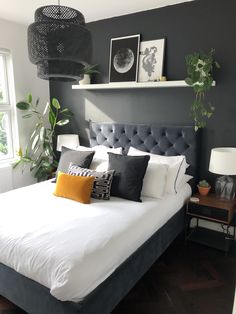 a bed with white sheets and black headboard in a bedroom next to a window