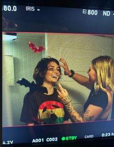 a woman is getting her hair done by another woman in front of a mirror with butterflies on it