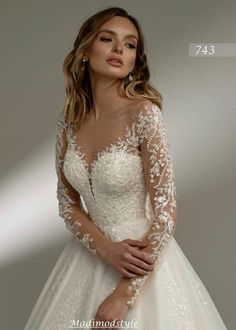 a woman wearing a wedding dress with long sleeves and lace on the bouncy