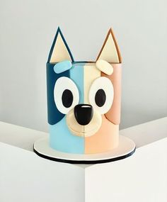 a cake shaped like a dog on top of a white plate with blue and pink frosting