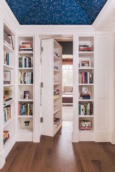 an open book case with books on it in the middle of a wooden floored room