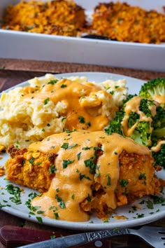 a white plate topped with meat covered in gravy next to mashed potatoes and broccoli