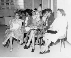 an old black and white photo of women sitting in front of each other on chairs