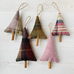 three small christmas trees are hanging from clothes pins on a white wooden background with wood pegs