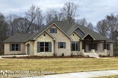 a brick and stone house in the middle of a grassy area with trees behind it