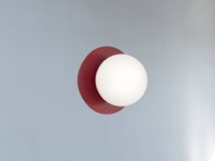 a red and white object is suspended in the air on a gray background with light coming from behind it