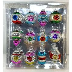 an assortment of christmas ornaments in a clear box