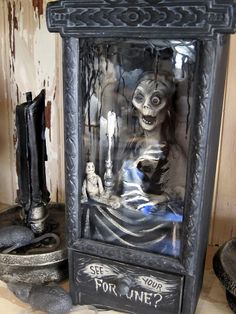 a creepy doll in a glass case on top of a wooden table next to other items